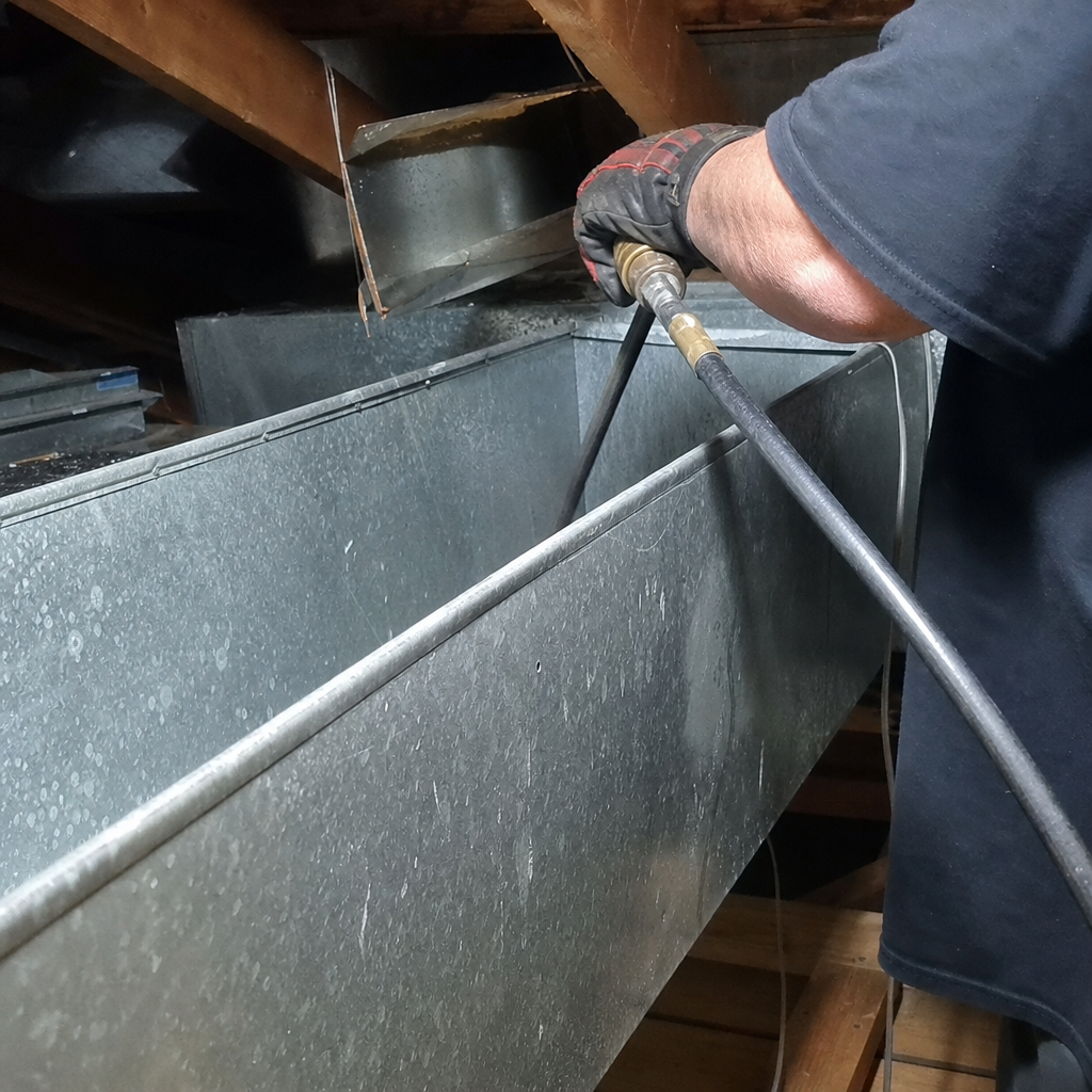 Professional technician performing residential air duct cleaning service in attic in Buffalo, NY